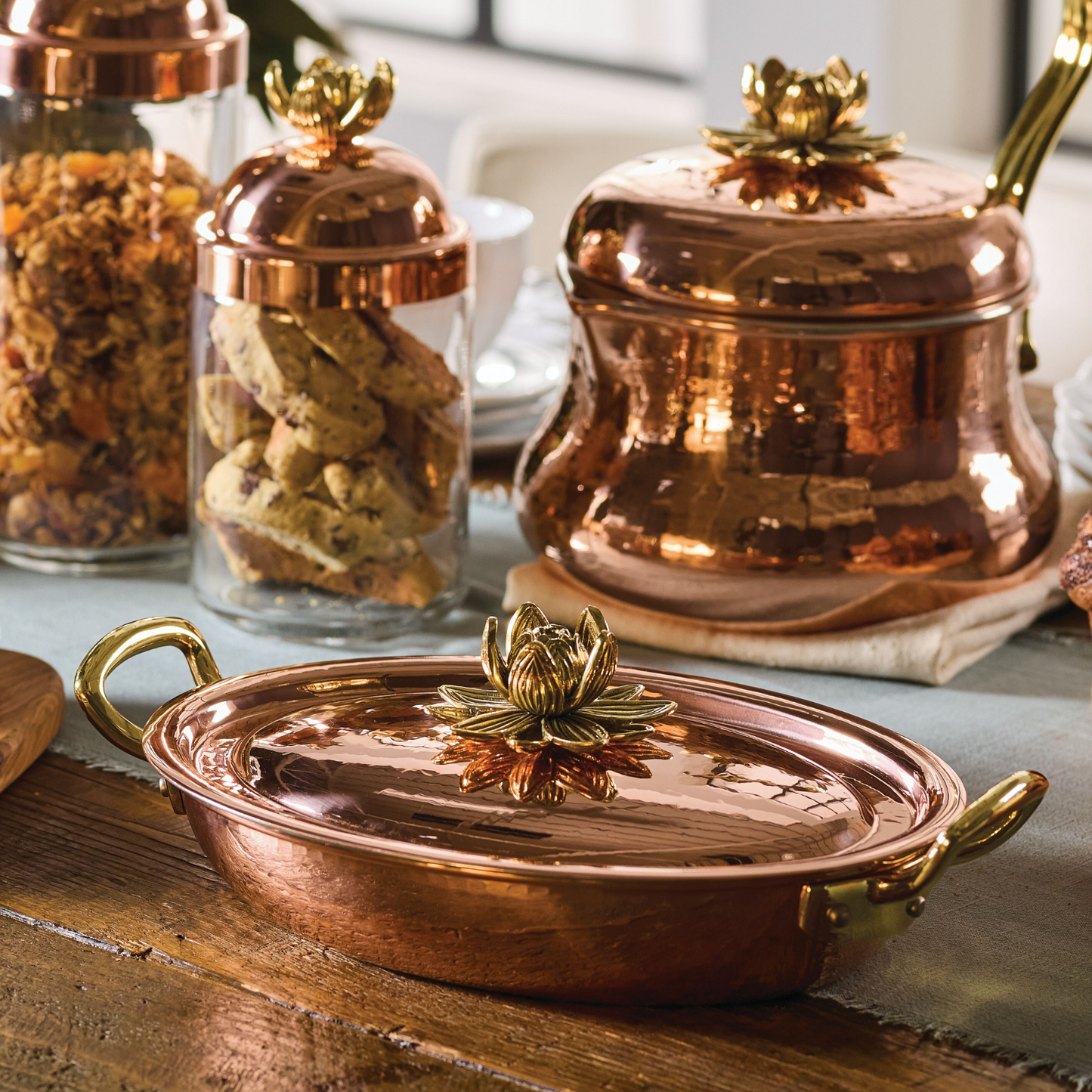 Hammered copper 10" covered oval gratin, tin-lined by hand over fire, with bronze handles. Shown with matching tea kettle and Lotus glass jars from the Ruffoni Historia collection