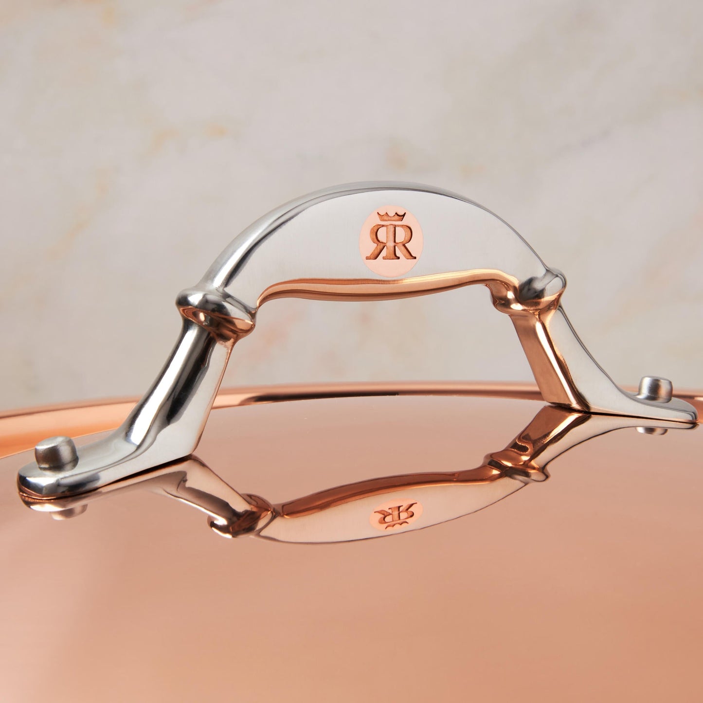 Comfortable lid handle in stainless steel with decorative inlaid copper coin by Ruffoni