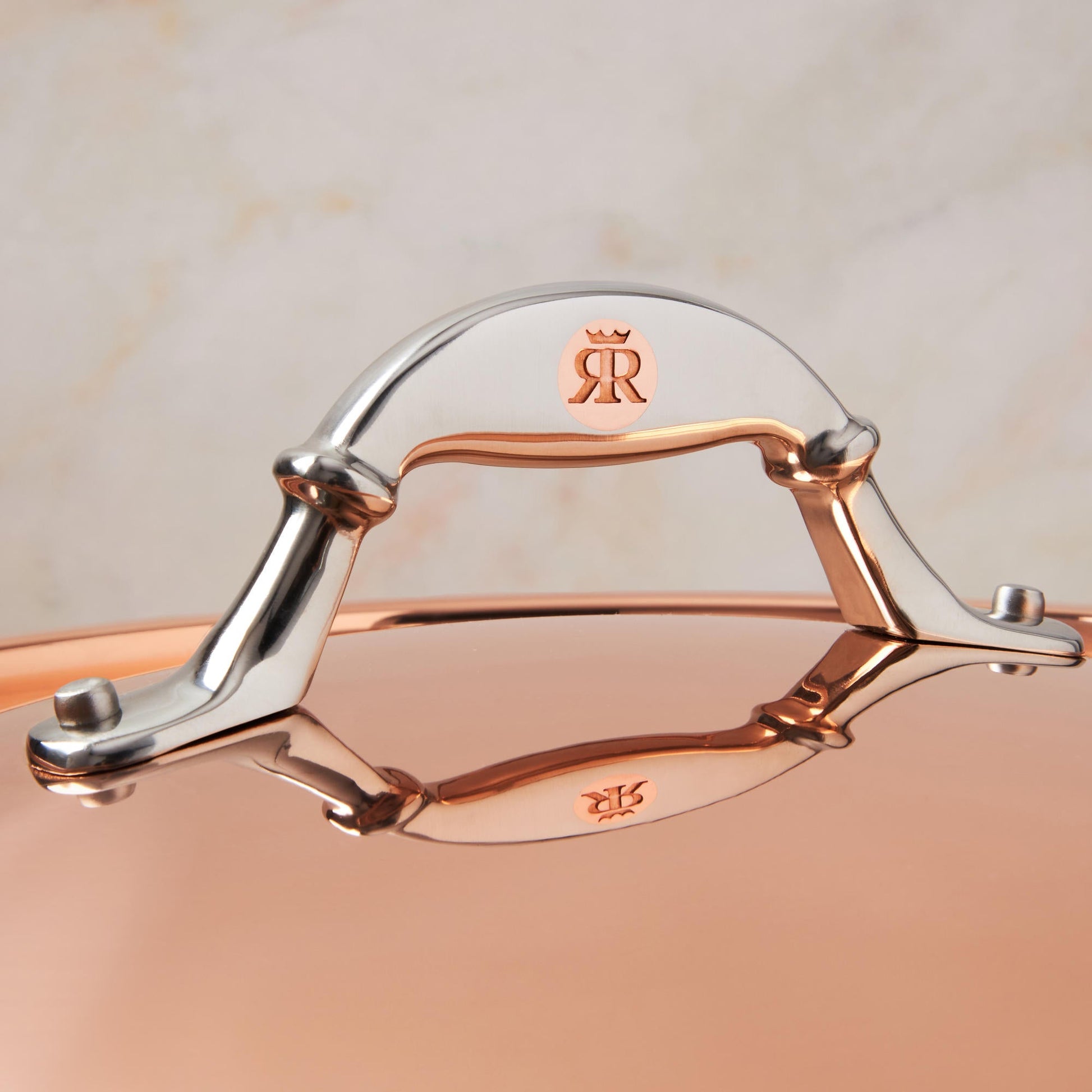 Comfortable lid handle in stainless steel with decorative inlaid copper coin by Ruffoni