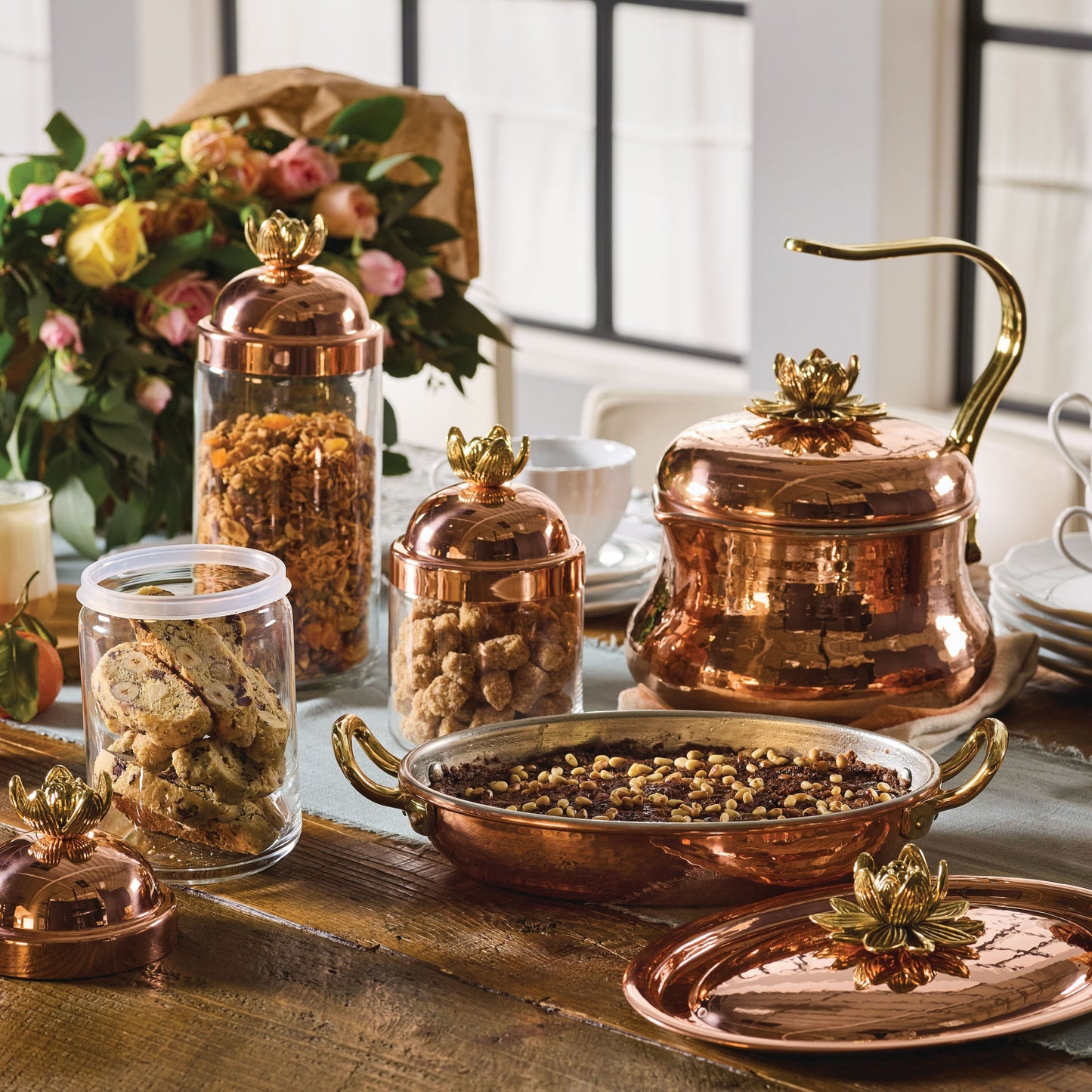 lotus 5 piece set including a copper tea kettle, copper 10" roaster and a set of 3 kitchen glass jars in glass and copper, all topped by lotus-shaped bronze knobs