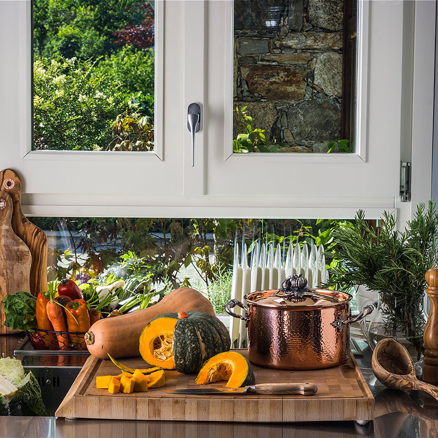 Soup pot in the kitchen with bunches of fresh veggies, including butternut and acorn squash