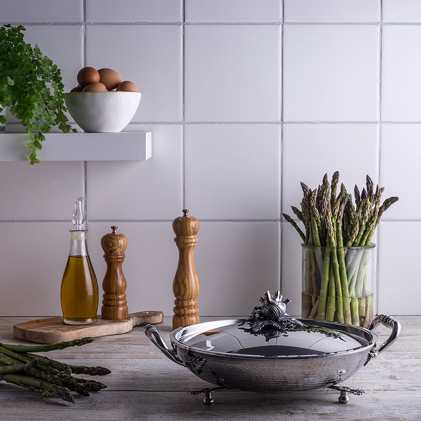 Stainless steel gratin in kitchen with eggs, oil, and asparagus