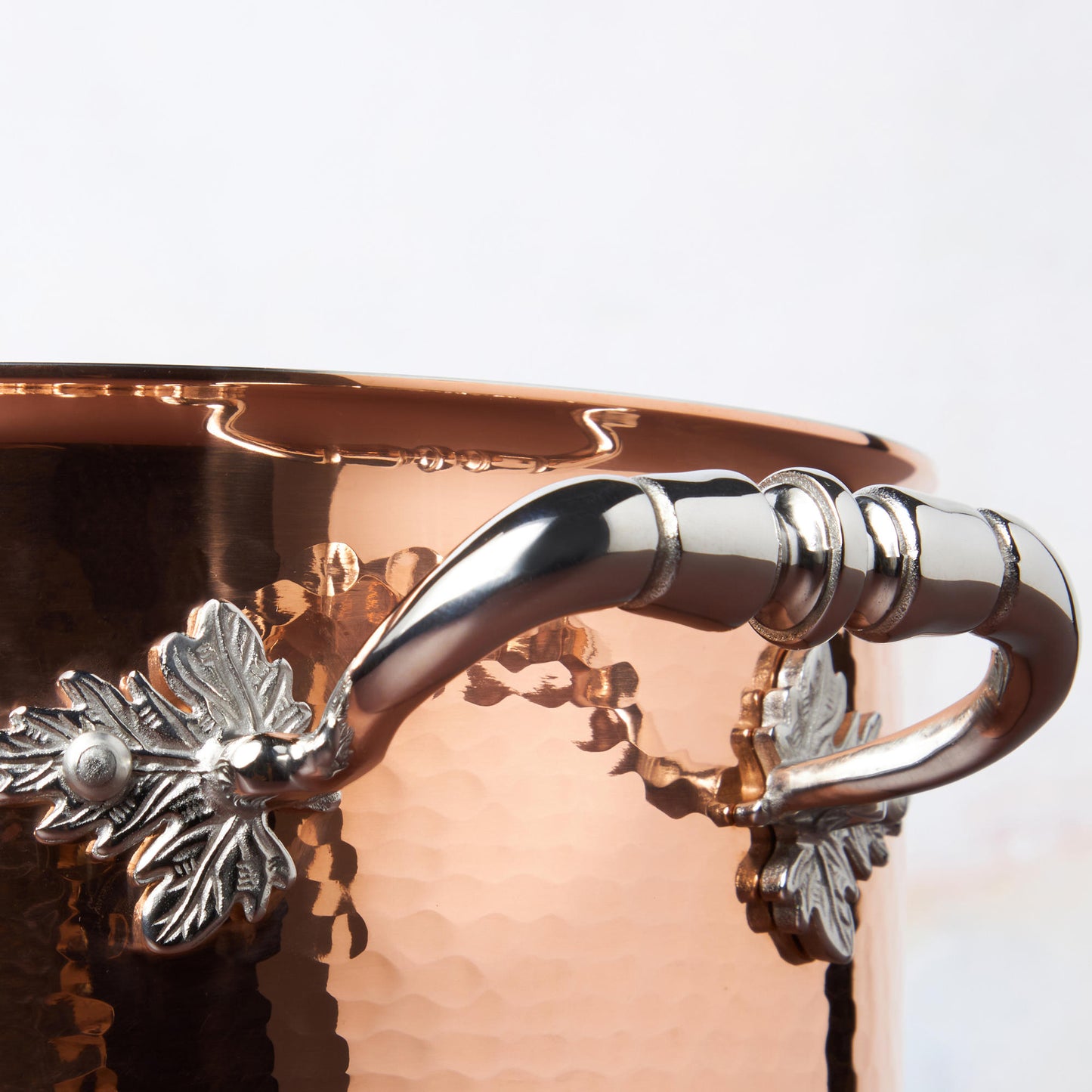 Beautiful stainless steel helper handle decorated with delicate leaves on Opus Cupra cookware by Ruffoni