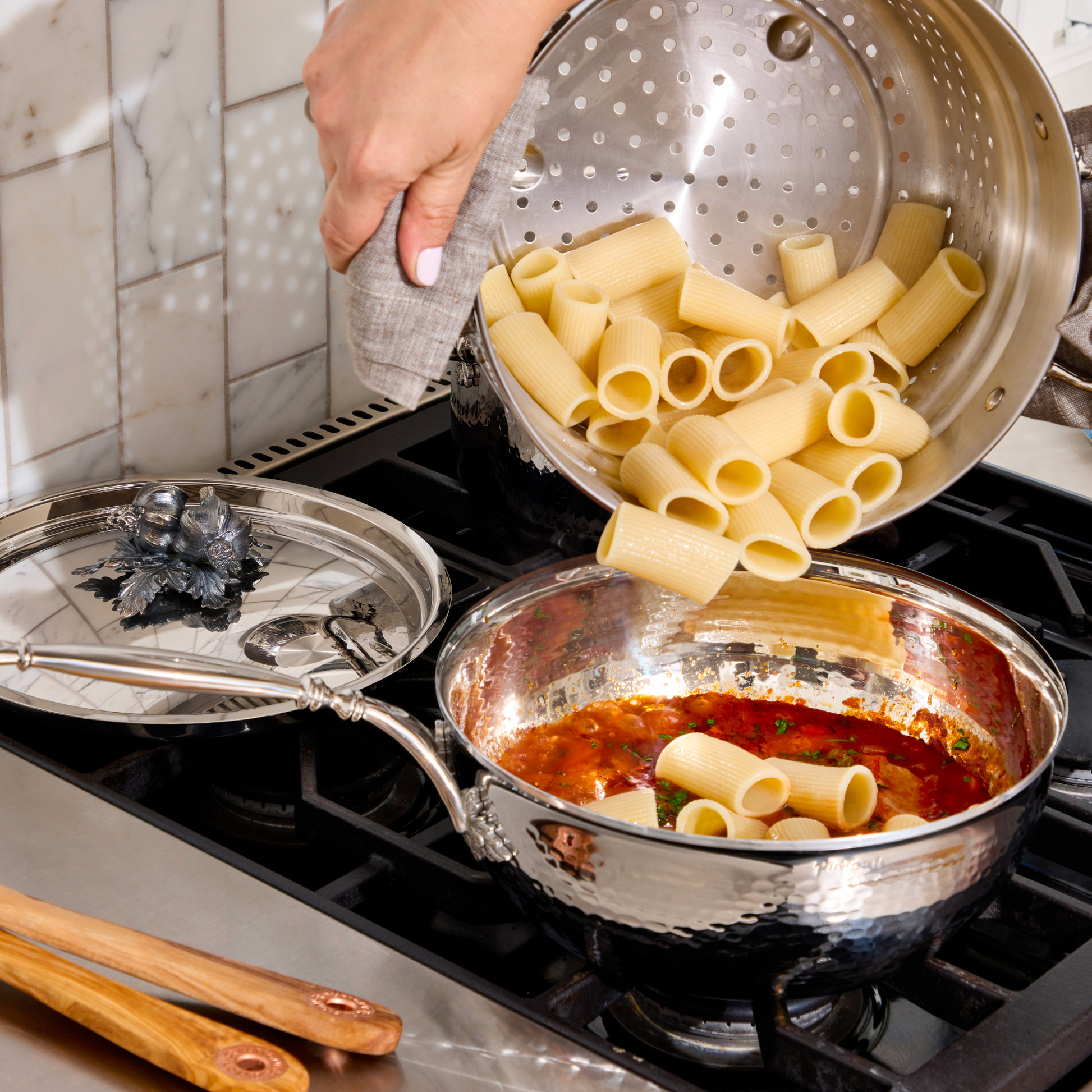 Tomato tuna sauce pasta with rigatoni in an Opus Prima hammered-clad stainless steel chef's pan decorated silver-plated lid knob finial from Ruffoni.