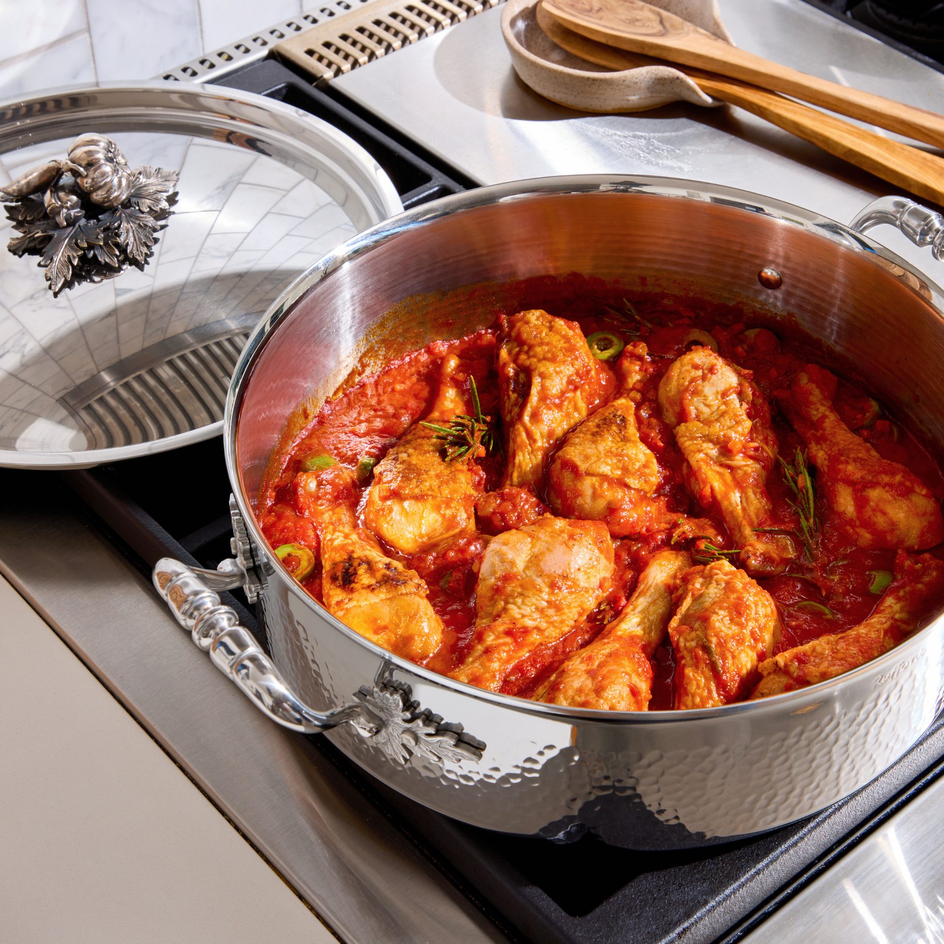 Chicken cacciatore with green olives in an Opus Prima hammered-clad stainless steel braiser with decorated silver-plated lid knob finial from Ruffoni