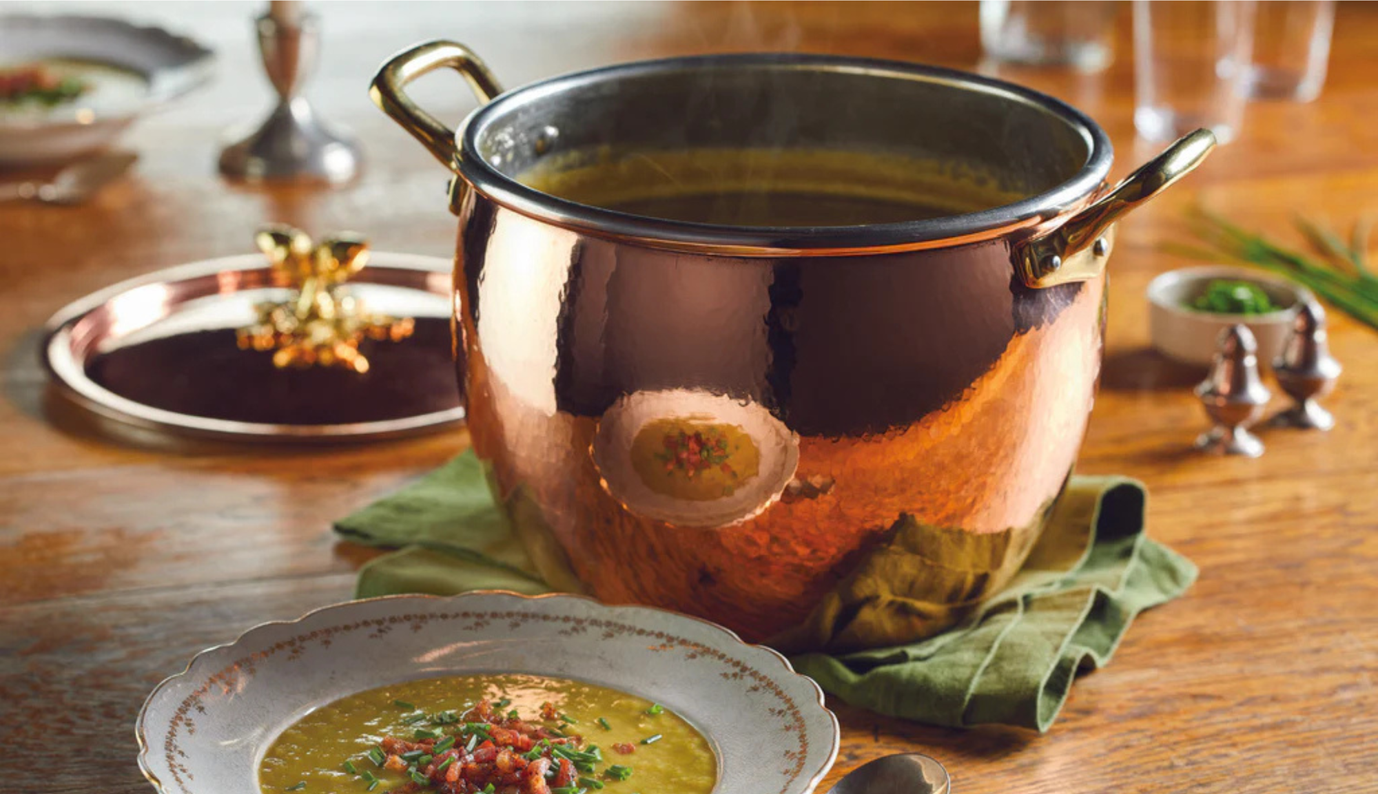 Copper pot with soup on a wooden table