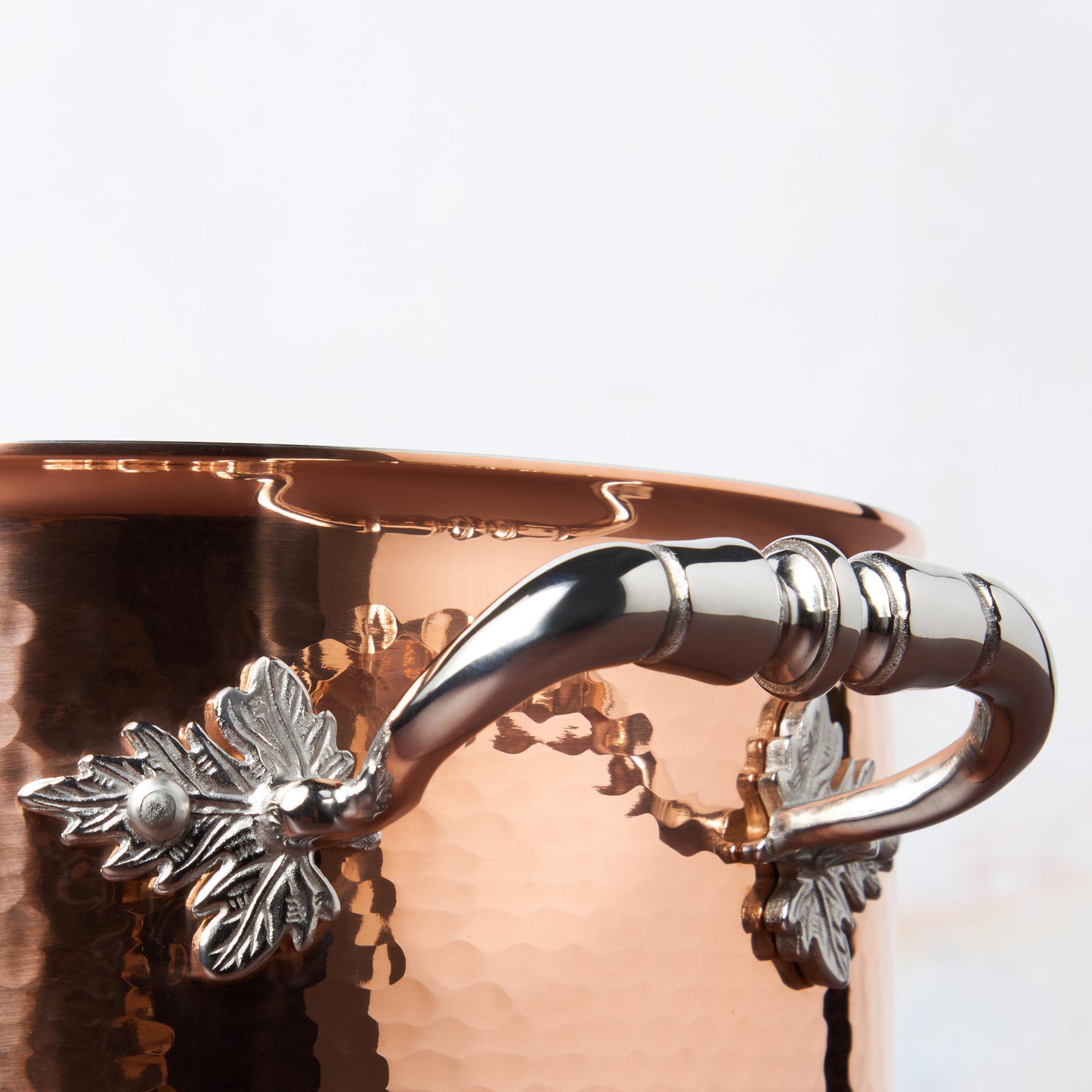 Beautiful stainless steel helper handle decorated with delicate leaves on Opus Cupra cookware by Ruffoni