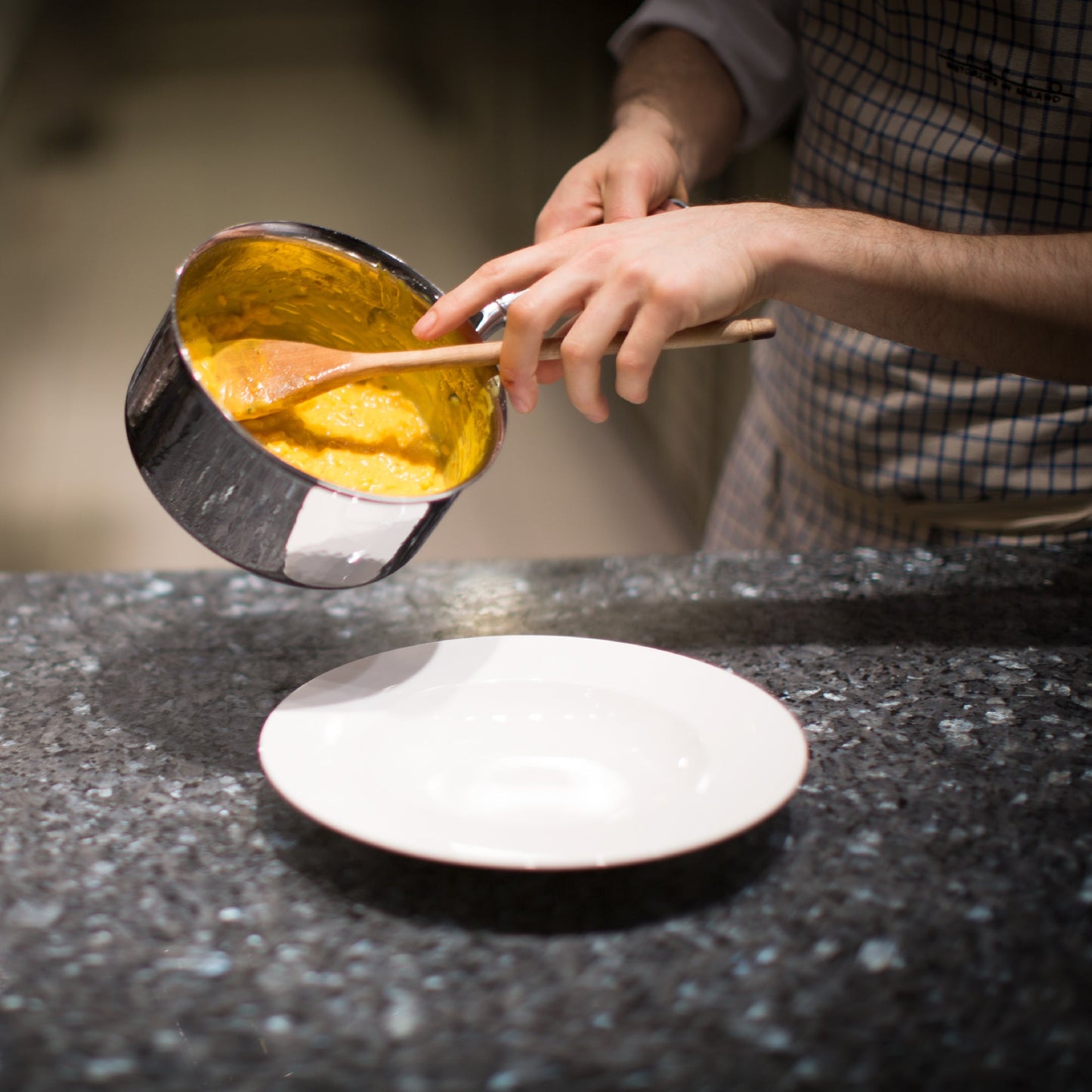 Italian chef pouring saffron risotto from hammered stainless steel saucepan by Ruffoni